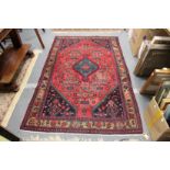 A Persian rug, red ground with stylized decoration.