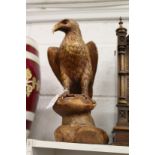 A carved wood model of an eagle on a rock.