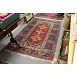 A Persian rug, red ground with large central cross shaped motifs.