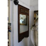 A decorative hardwood framed mirror with carved and painted panels.