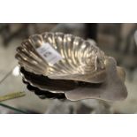 Three silver shell shaped butter dishes.