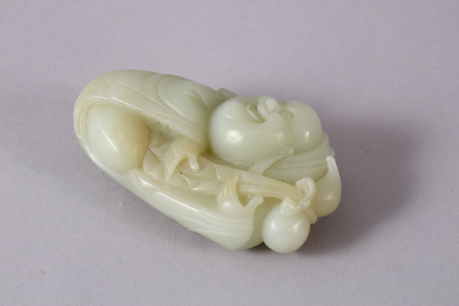 A CHINESE CARVED JADE FIGURE / PENDANT OF BUDDHA, in a recumbent position holding a tied double - Image 2 of 3