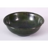 A PLAIN CHINESE CIRCULAR JADE BOWL, with mottled decoration, signed on base, 12cm diameter.
