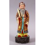 A 19TH / 20TH CENTURY CHINESE FAMILLE ROSE PORCELAIN FIGURE OF AN IMMORTAL, stood upon a wood