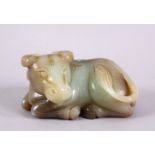 A CHINESE CARVED JADE FIGURE OF A RECUMBENT COW / OX, in a recumbent pose bearing a grin, 12cm
