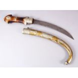 A LARGE SAUDI ARABIA JAMBIYA DAGGER, With a carved wooden handle, metal mounted sheath, 64cm long.