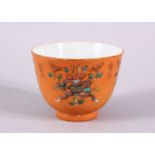 A CHINESE ORANGE GROUND PORCELAIN CUP, with an orange ground and precious object decoration, the
