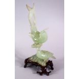 A CHINESE CARVED GREEN JADE FIGURE OF TWO BIRDS, both seated upopn a naturalistic formed branch,