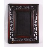 A CHINESE CARVED HARDWOOD FRAME, carved with openwork of flora, 26cm x 20cm.`