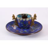A CHINESE CLOISONNE TEA CUP AND SAUCER, upon a blue ground with lotus decoration, 6cm high x 13cm