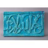 A GOOD IRAN KASHAN TURQUOISE GLAZED POTTERY CALLIGRAPHIC PANEL, with a turquoise glaze over