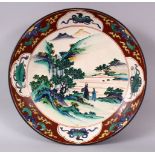 A JAPANESE MEIJI PERIOD KUTANI CHARGER, decorated with scenes of figures in native landscapes, the