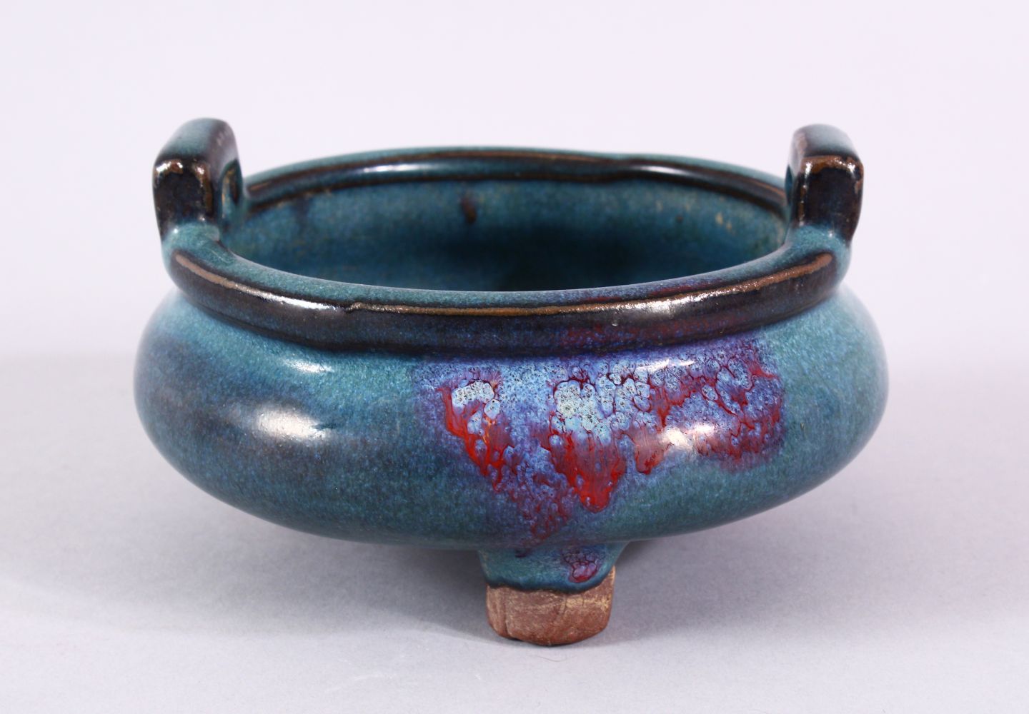 A CHINESE JUN WARE TWIN HANDLE CENSER, with a graduated blue to red glaze, twin handles and tripod