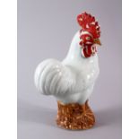 A CHINESE PORCELAIN FIGURE OF A COCKEREL, seated upon stylized wooded stump, red lacquer facial