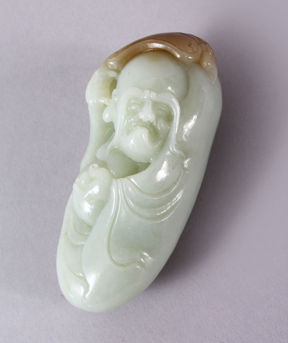 A CHINESE CARVED JADE FIGURE / PENDANT OF AN IMMORTAL, holding an object and a fan above his head,