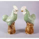 A PAIR OF CHINESE CELADON GLADE PORCELAIN MODEL CHICKENS, each upon a stylized rocky outcrop, with a