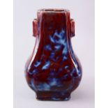 A CHINESE FLAMBE GLAZED PORCELAIN VASE, the gu shaped vase with an ox blood red ground with white