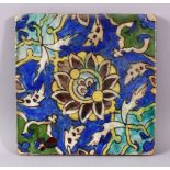 A SMALL SQUARE FORMED QAJAR POTTERY TILE SECTION, with underglaze blue and floral motif decorations,