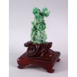 A GOOD GREEN JADITE CARVING OF FLOWERS, 13cm high, on a carved wooden stand.