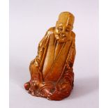 A CHINESE CARVED SOAPSTONE FIGURE OF A JOLLY MAN, in seated position, 11cm