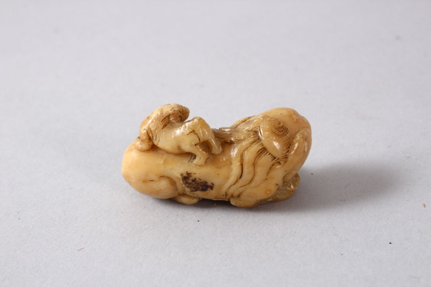 A CHINESE SOAPSTONE FIGURE OF A LION DOGs, the small carving depicts a recumbent lion dog with a - Image 2 of 4