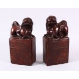 A PAIR OF UNUSUAL TERRACOTTA / POTTERY LION DOG SEAL / DESK WEIGHTS, each dog modeled with their paw
