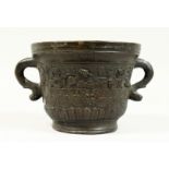 A TWO HANDLED BRONZE MORTAR, with serpent handles, the body with masks and fruiting vines. Dated
