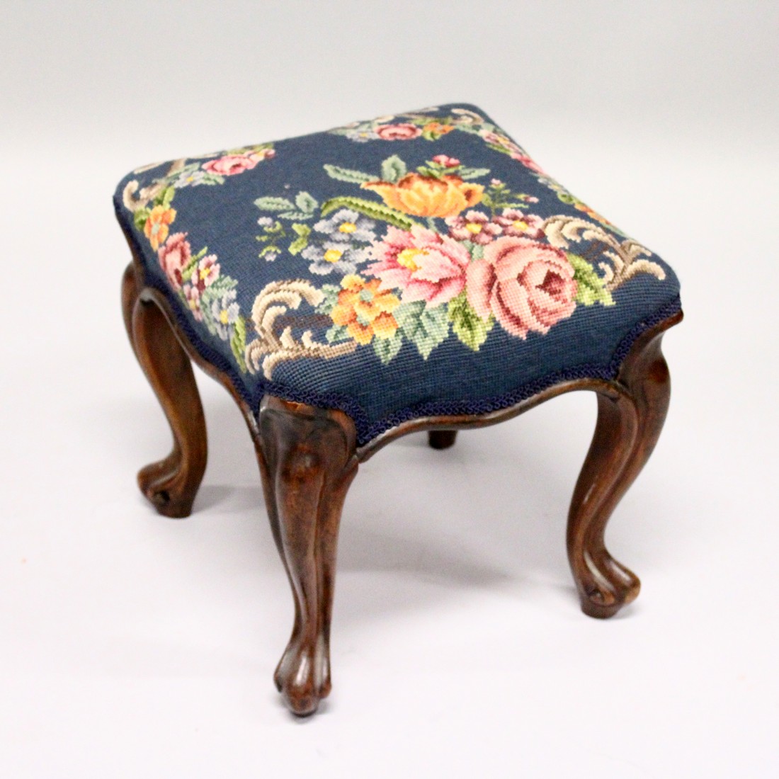 A VICTORIAN ROSEWOOD SQUARE TOP STOOL with floral needlework on cabriole legs. 1ft 1ins long.