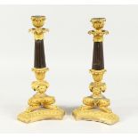 A SUPERB PAIR OF EMPIRE BRONZE AND GILT BRONZE CANDLESTICKS on claw feet with triangular bases.