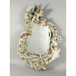 A LARGE PORCELAIN MIRROR in the MEISSEN style, encrusted with flowers, cherubs and scrolls. 32ins