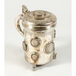 A CONTINENTAL .835 SILVER TANKARD AND COVER inset with silver coins on three lion feet. 6.5ins