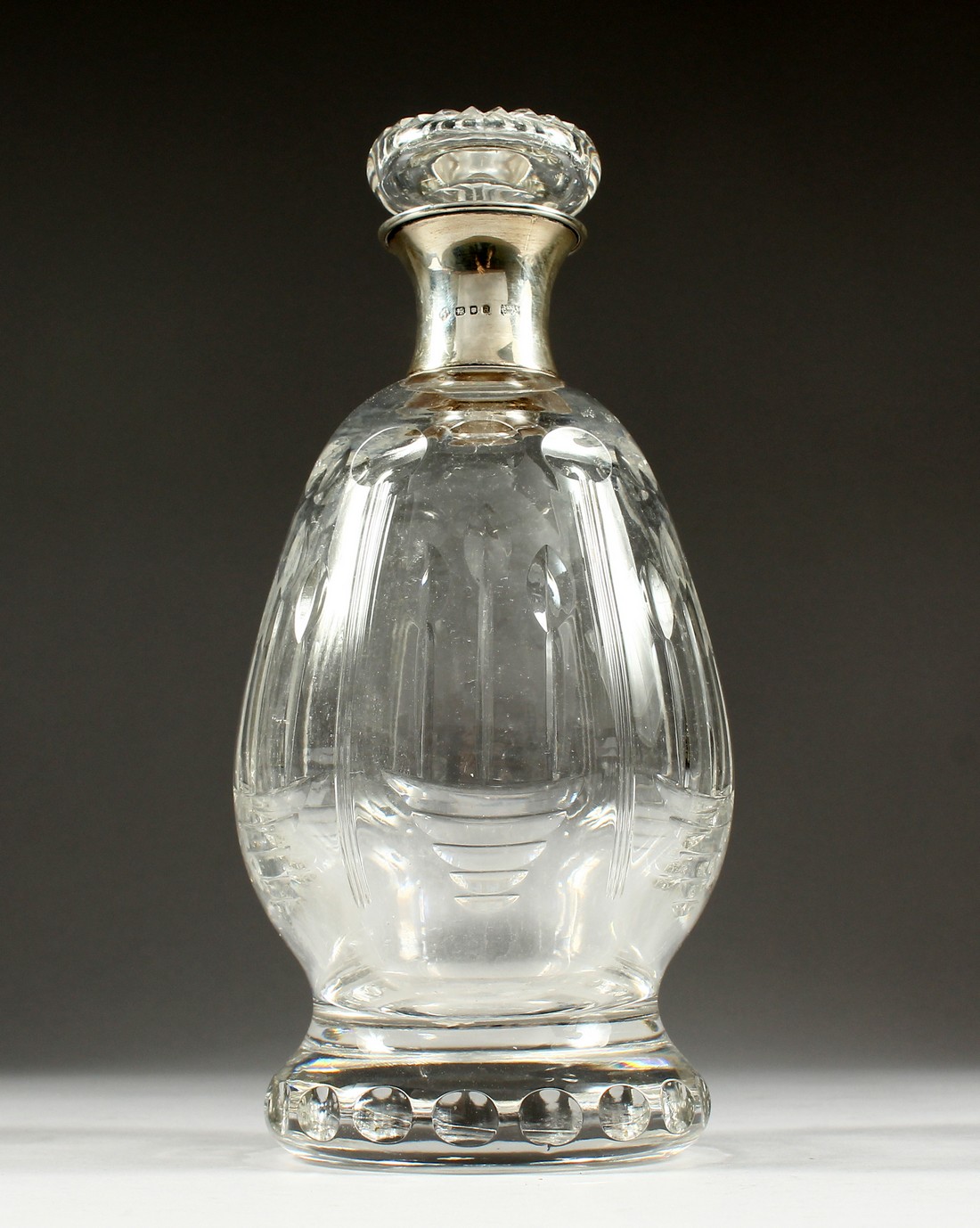 AN ASPREY CUT GLASS DECANTER AND STOPPER with silver band.