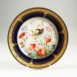 A SEVRES CIRCULAR PLATE with bule gilt border, the centre painted with flowers and a bird, signed