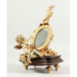 A GILT BRONZE CUPID MIRROR on a marble base. 12ins high.