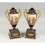 A GOOD PAIR OF VIENNA PORCELAIN TWO HANDLED URNS ON STANDS, rich blue and gilt ground painted with