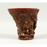 A LARGE CHINESE LIBATION CUP carved with figures, probably resin. Signed, 5ins high.