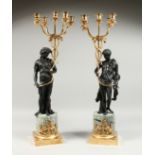 A VERY GOOD PAIR OF BRONZE CLASSICAL CANDELABRA on classical figures holding five candles, on a