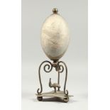 AN AUSTRALIAN EMU EGG with plated mount and wooden base, etched with an eagle. Egg 5ins.