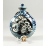 A STUDIO POTTERY WINE BOTTLE, pierced and moulded with a tree design. 10ins long