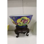 A Chinese circular porcelain bowl painted with panels of flowers on a hardwood stand.