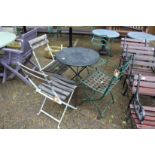 A small metal folding table and two pairs of wrought iron chairs.