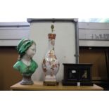 A bust of a young girl a pottery lamp and a painted cabinet.