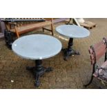 A pair of circular zinc topped tables with cast iron bases.