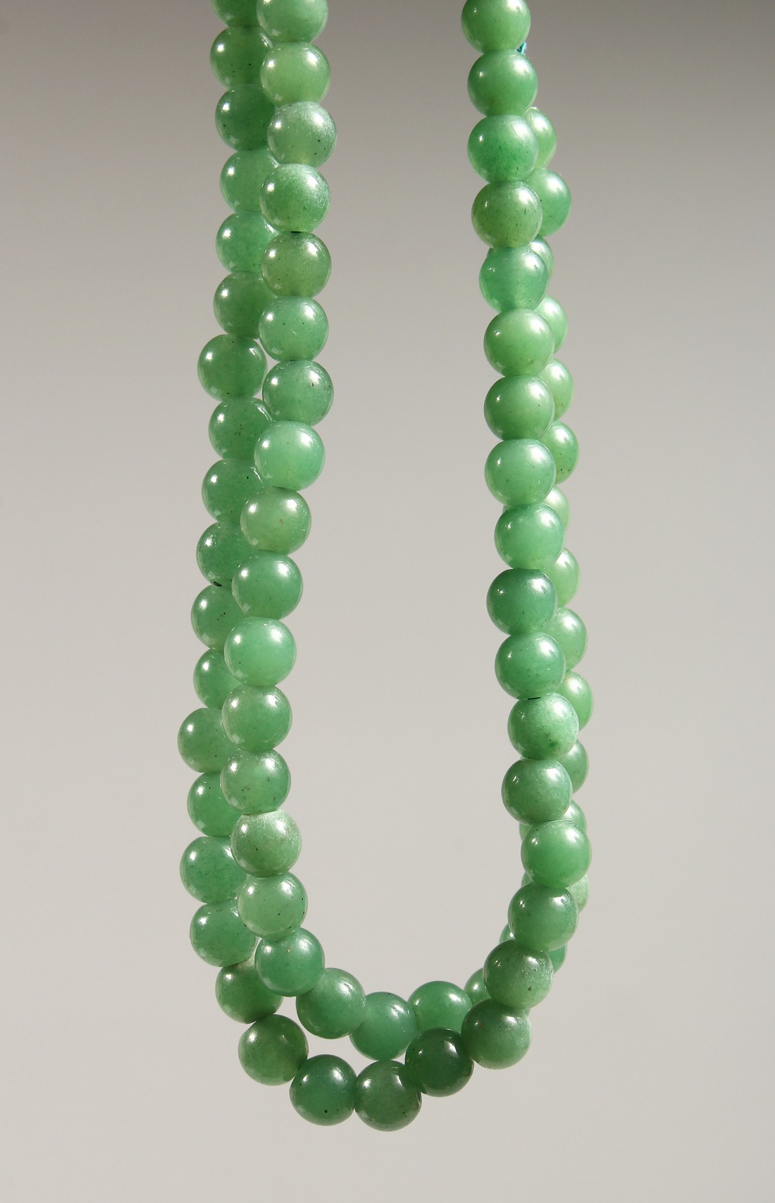 A STRING OF JADE BEADS 24ins long.