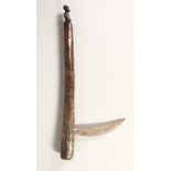 A TRIBAL WOOD AND METAL AXE carved with a figure. 24 ins long