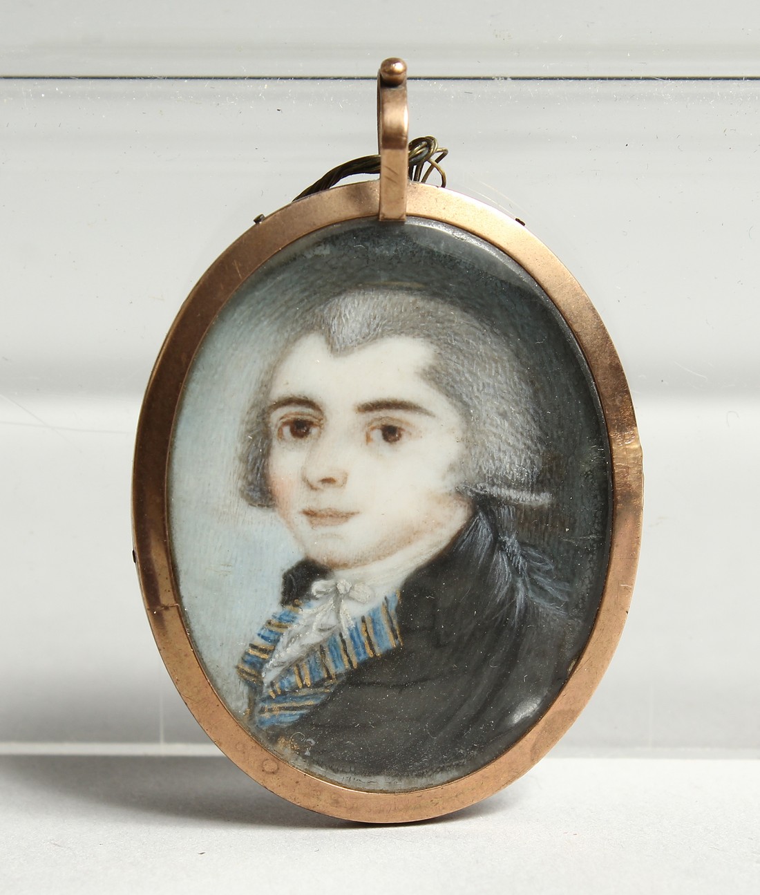 A GEORGIAN OVAL MINIATURE OF A YOUNG MAN, the reverse with plated hair. 1.25ins x1.25ins