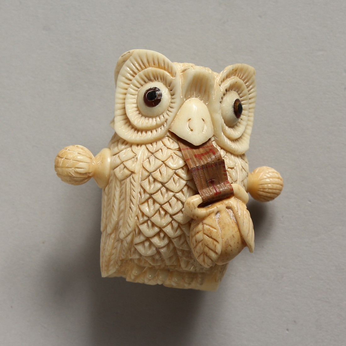 A CARVED BONE OWL TAPE MEASURE