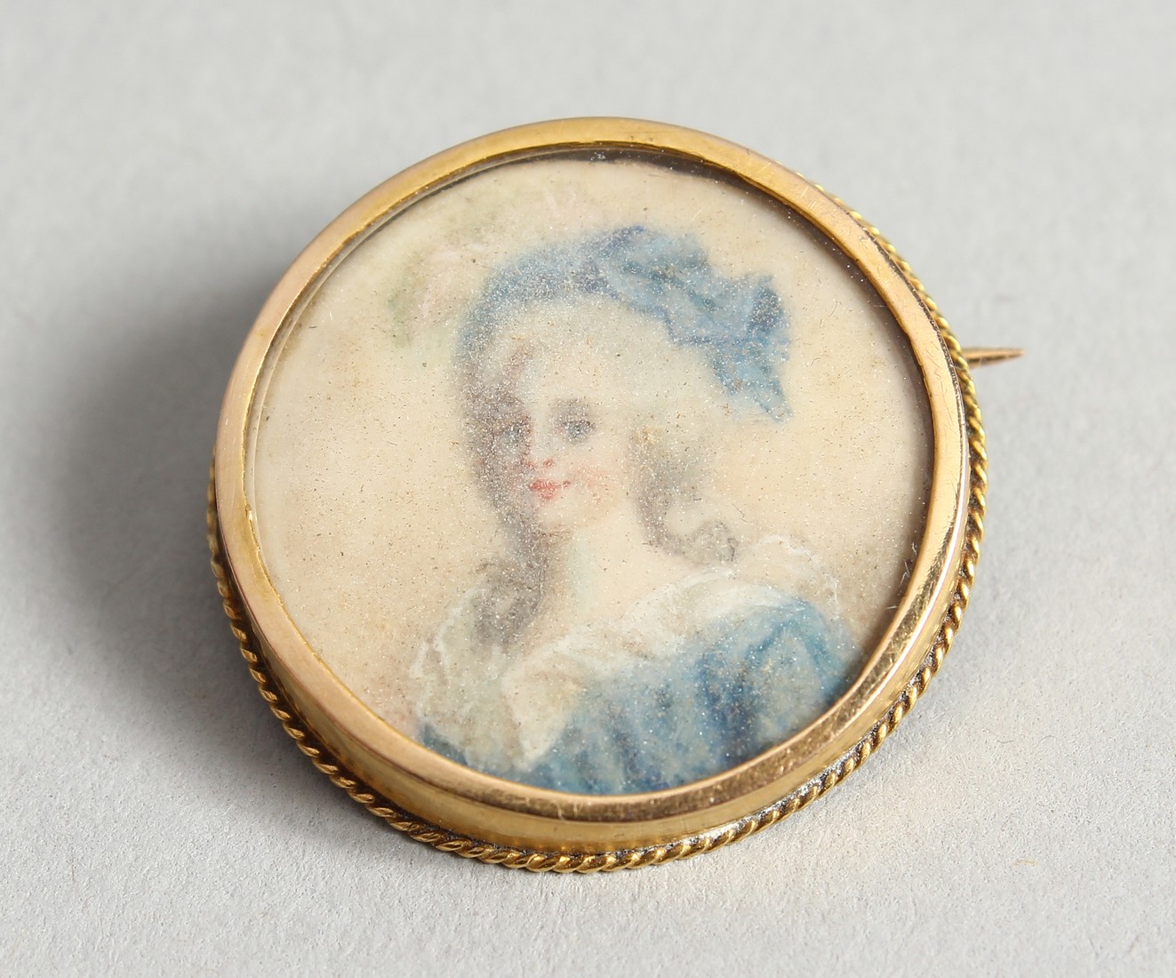 A SMALL 18 CT GOLD MINIATURE of a lady, as a brooch.