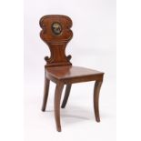 A GEORGE III MAHOGANY HALL CHAIR with solid seat, the shaped back with a painted crest.