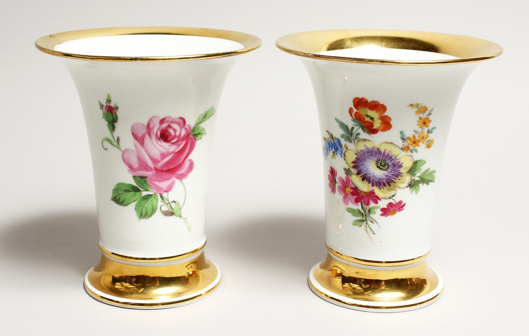 A GOOD PAIR OF MEISSEN TRUMPET SHAPED VASES edged in gilt and painted with roses. Cross sword mark